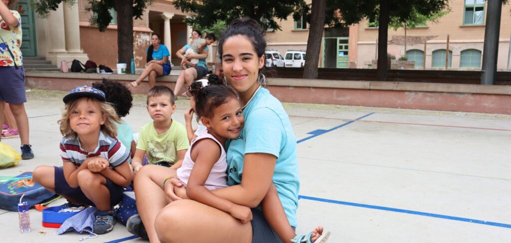 Monitora abraçada a infants en un casal al pati de l'escola