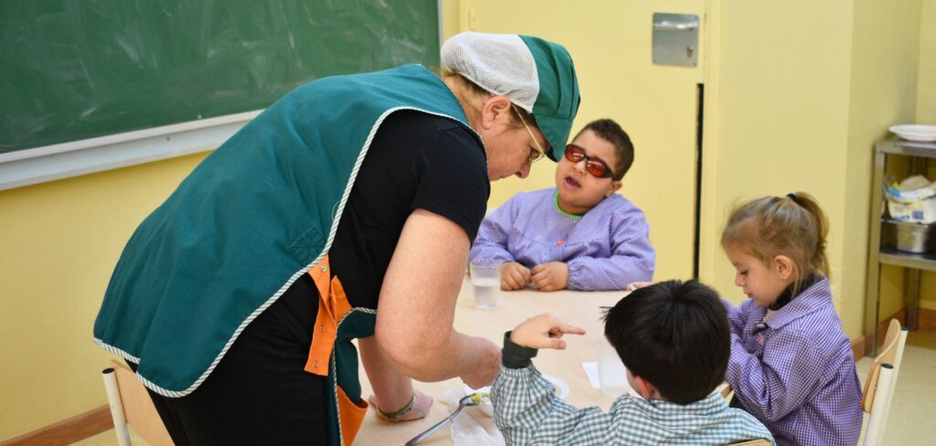 Monitora de menjador amb infants a l'aula